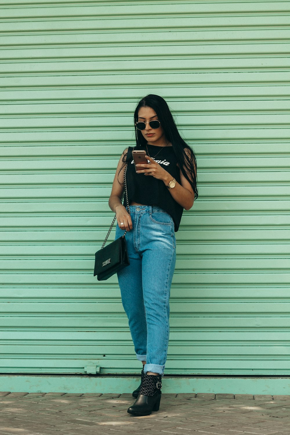 Mujer en top negro sin mangas sosteniendo el teléfono inteligente al aire libre