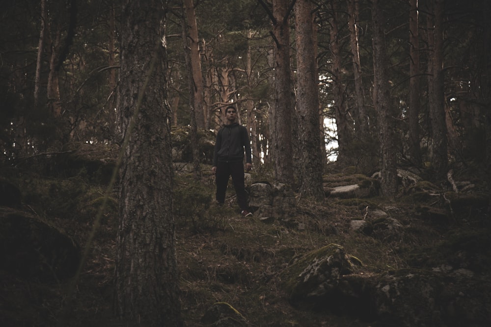 man standing near tall and green trees