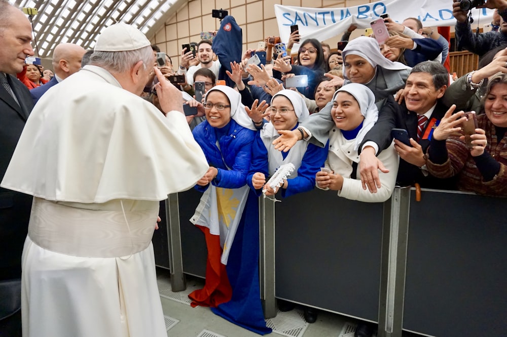 Papst Franziskus steht umgeben von Menschen