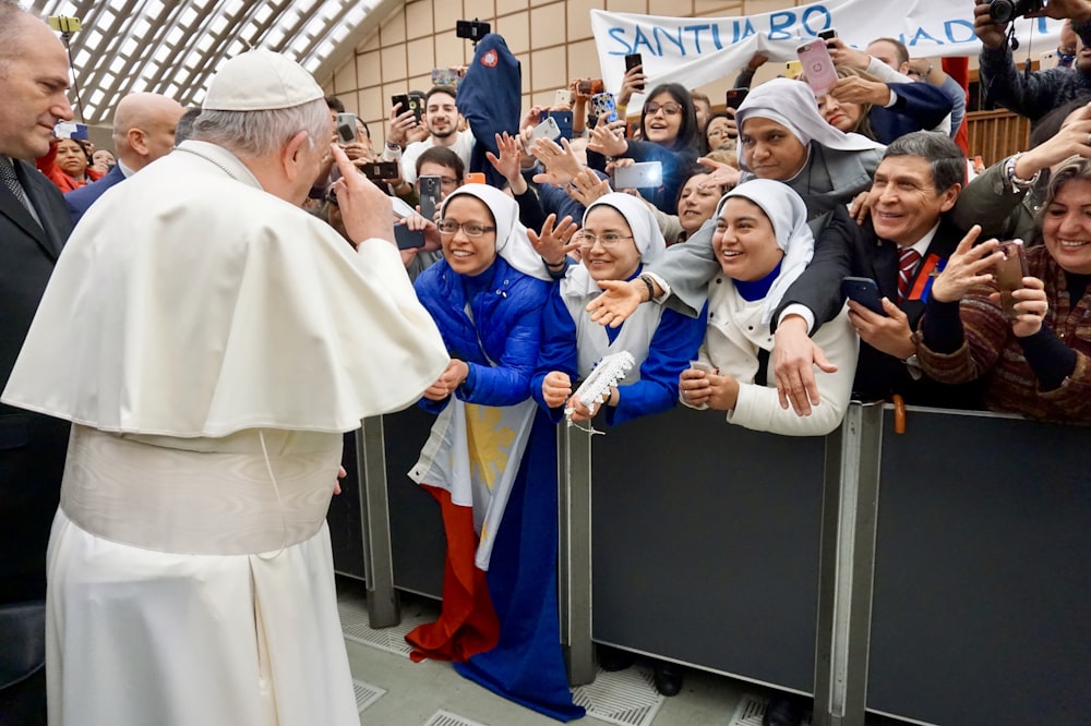 Papa Francisco de pé cercado de pessoas