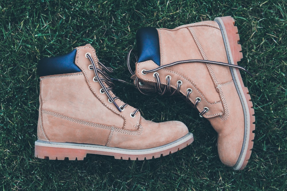 pair of brown-and-black work boots on green grass field during daytime