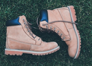 pair of brown-and-black work boots on green grass field during daytime