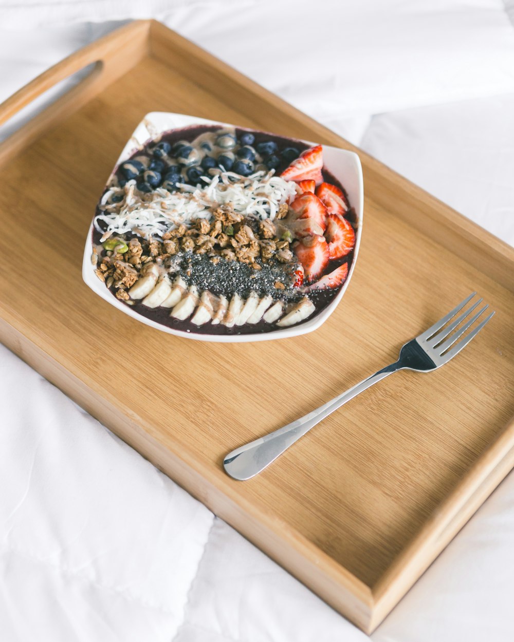 sliced fruit in bowl beside fork on brown serving tray