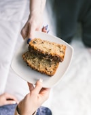 A cozy kitchen scene showing a baker’s hands slicing a warm banana bread loaf.