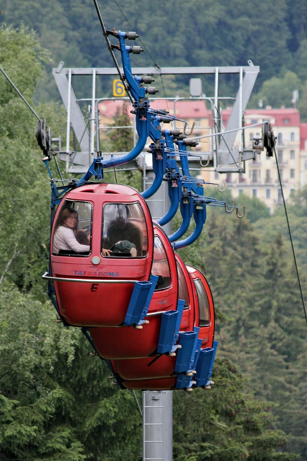 people sitting inside red cable cars during daytime