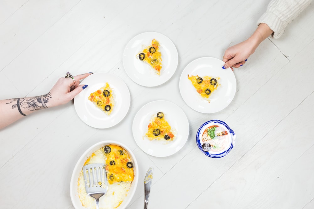 person holding plate of pizzas