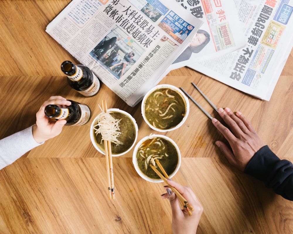 tres tazas de fideos en la mesa junto al periódico