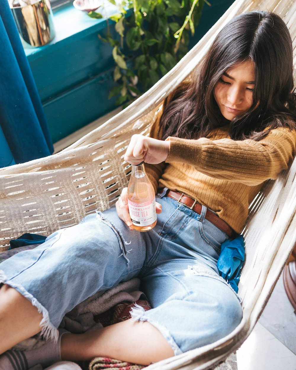 girl's wearing brown sweater on white hammock