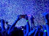 crowd of people taking a picture of person performing on stage