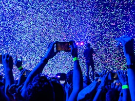 crowd of people taking a picture of person performing on stage