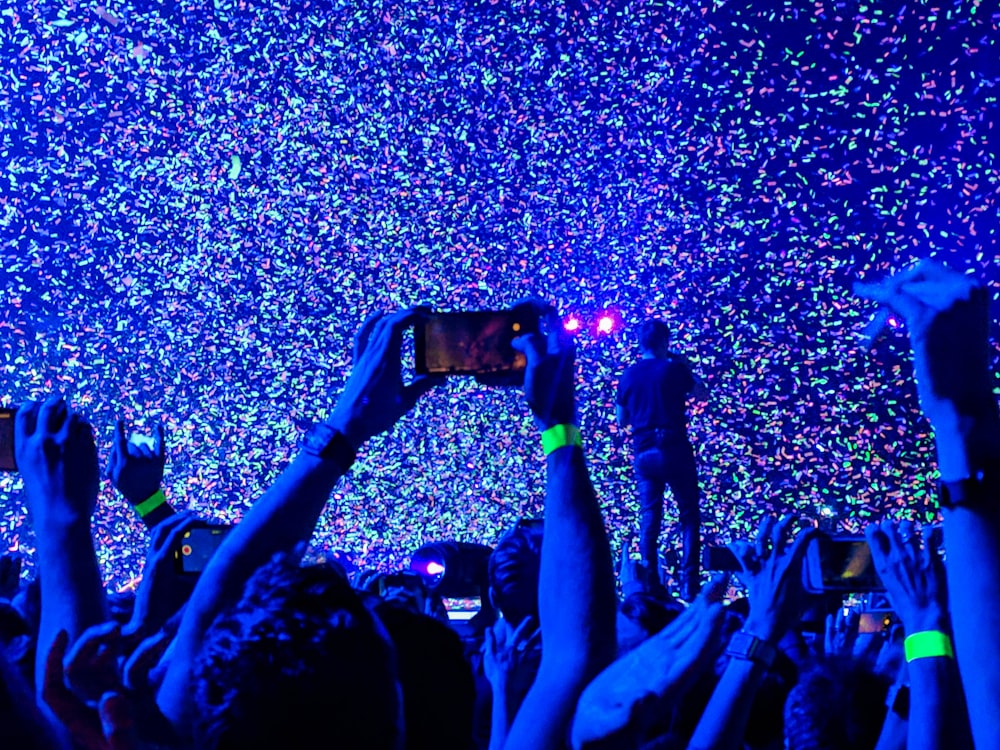 crowd of people taking a picture of person performing on stage