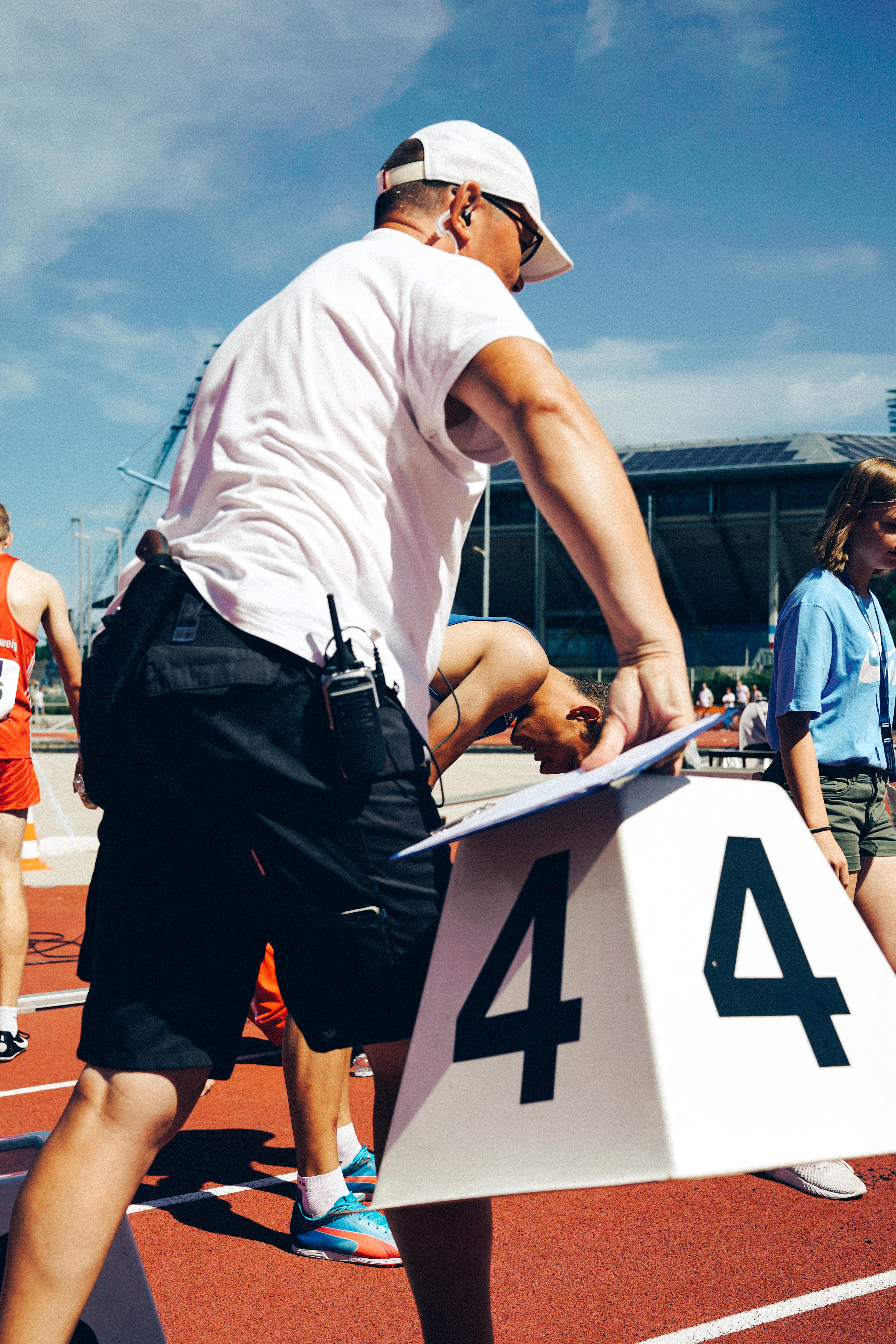 Atleta com camiseta branca ajustando o número na pista de corrida