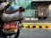 A motorcycle is carrying large, colorful woven bags filled with goods and small bouquets of greens. The background features a vibrant mural on a wall with the words 'LOVE DELHI' in bold white letters. There is a barred window next to the mural and a black and yellow striped curb. The scene is illuminated by sunlight, giving it a lively urban street vibe.