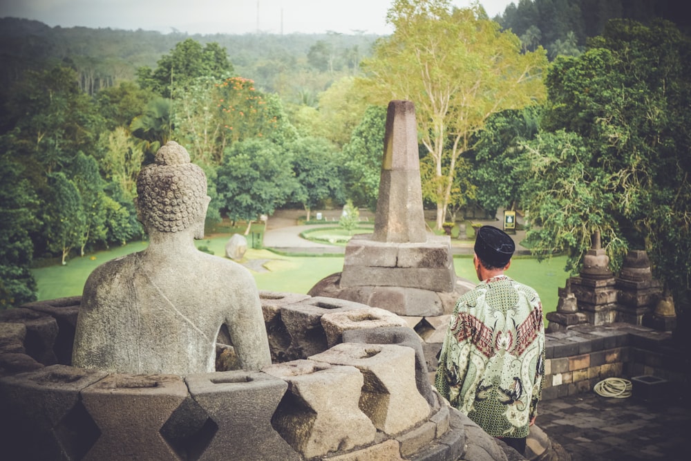 man sitting near concrete statue during daytime