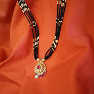 Elegant terracotta orange necklace resting on soft beige fabric, highlighting its cultural patterns.