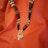 A beautifully crafted necklace featuring black beads with gold accents and a detailed pendant. The pendant includes intricate gold work, a central red stone, and white and pink hanging beads. The necklace is set against a rich orange fabric backdrop, adding to its elegance.