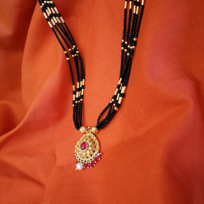 Traditional mangalsutra with black beads and gold-tone pendant, styled for bridal wear.