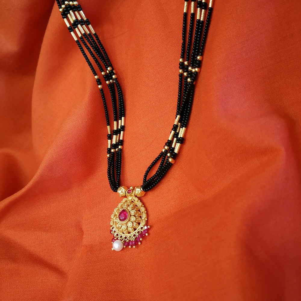 Collier à 4 rangs de perles beige, noir et or avec pendentif