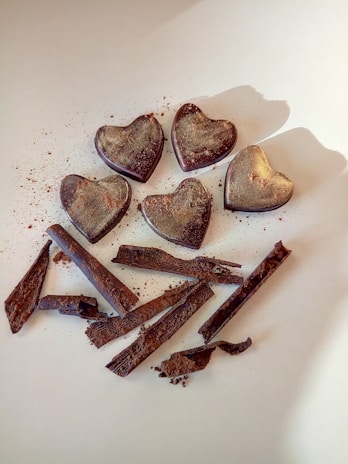 Close-up of a hand-decorated chocolate heart with delicate gold leaf accents on a dark background