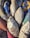 A collection of old, deflated sports balls, including footballs and volleyballs, arranged closely together. The balls display signs of wear, with faded colors and frayed surfaces. Text from brands such as 'Cosco' and 'Vega' is visible on some of them.