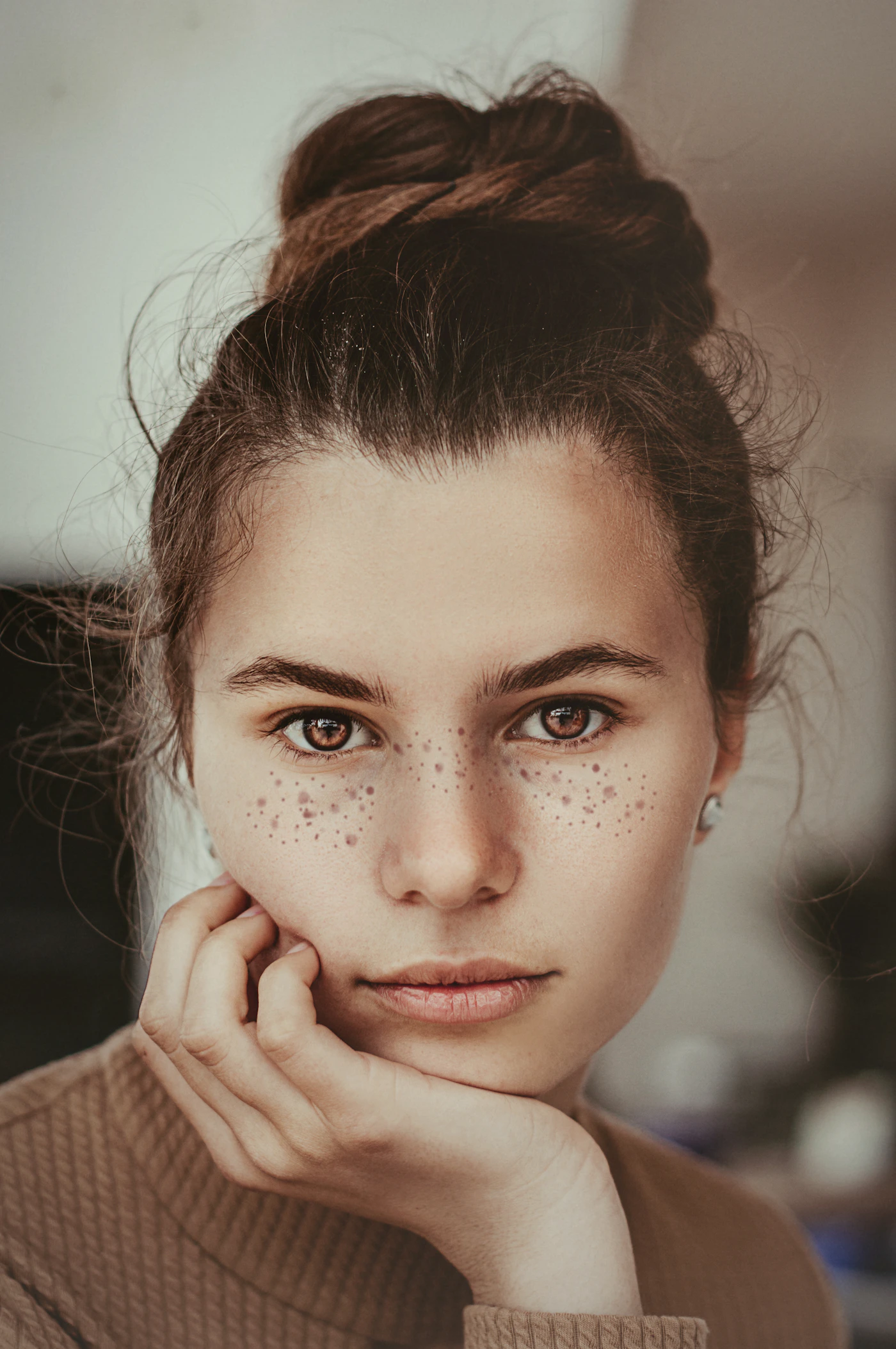 Close-up portrait of a woman gently framing her cheek with her hand, warm natural lighting drawing focus to her cheek and midface, representing the treatment area for cheek filler