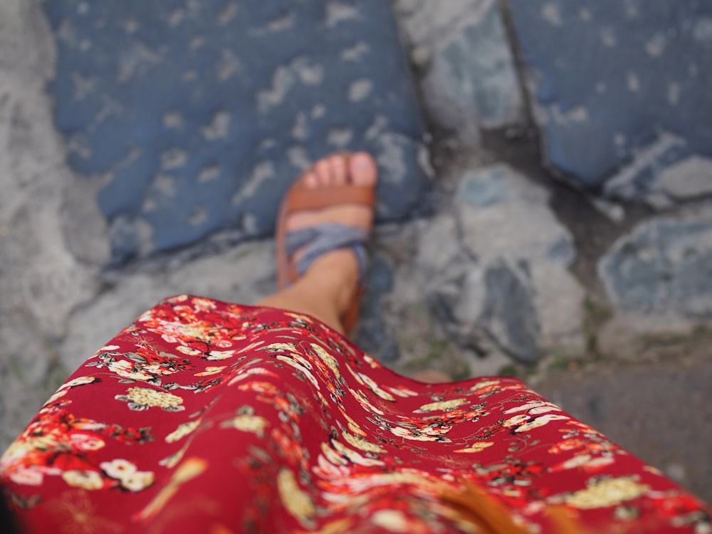 a woman's feet wearing sandals and a red dress