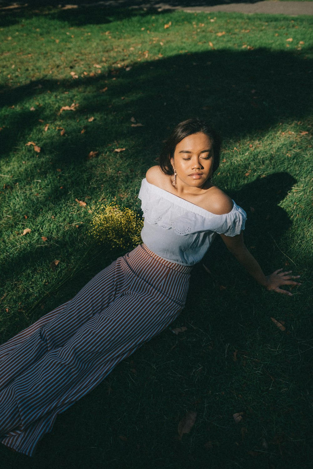 woman in white off-shoulder shirt sitting on grass field