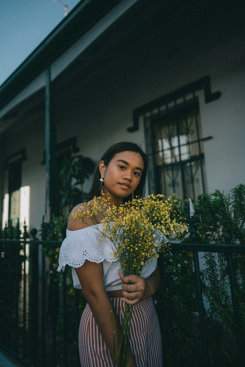 a woman holding a bouquet of flowers in front of a house