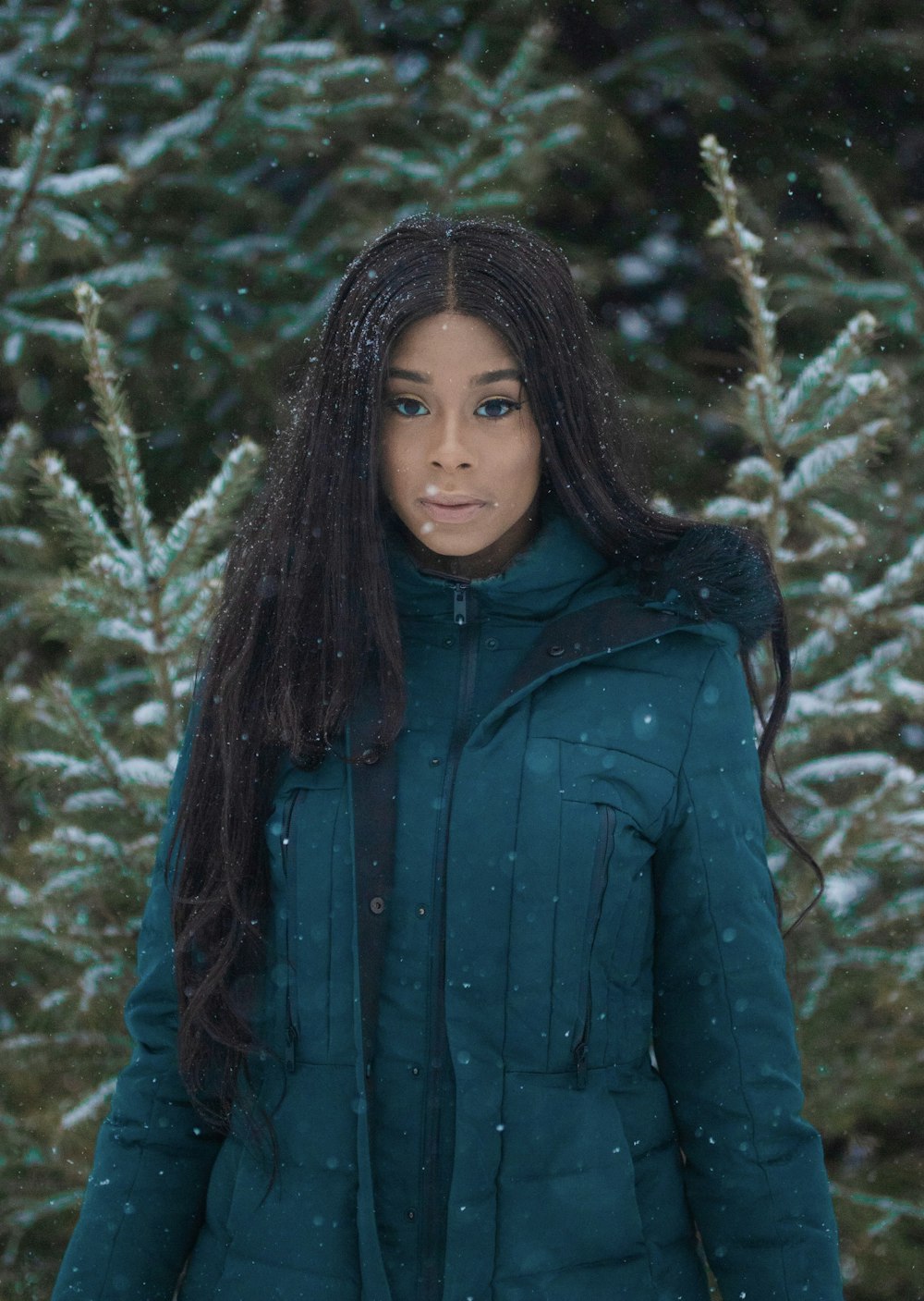 woman in blue jacket standing under the snow