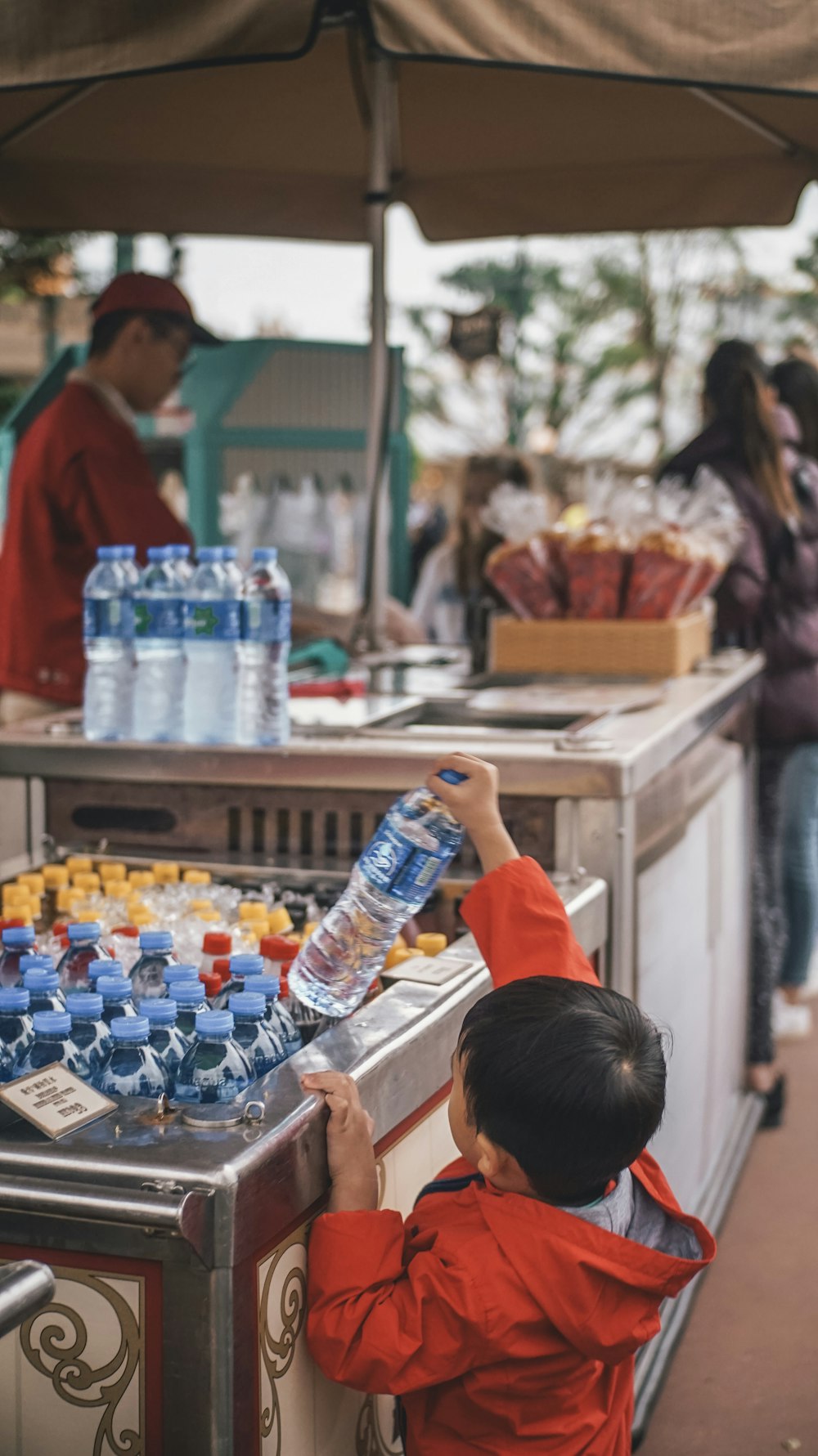 garçon tenant une bouteille en plastique bleue