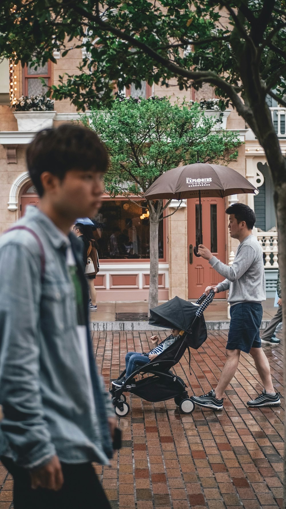 man holding umbrella while pushing stroller