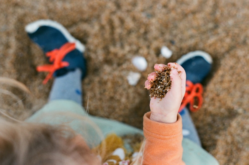 a little girl holding a handful of sand in her hand