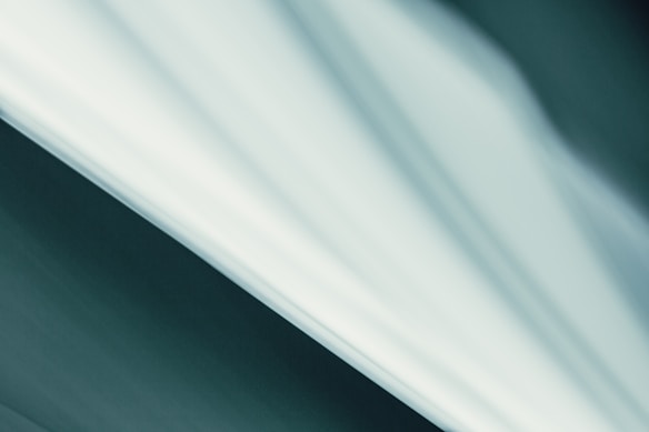 Abstract linear patterns with a gradient of soft white and teal colors create a serene and minimalist composition.