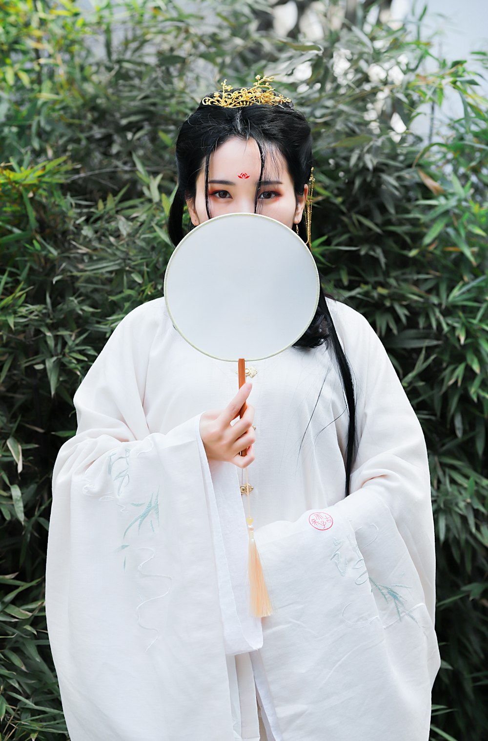 woman wearing kimono costume standing and covering her face using handfan