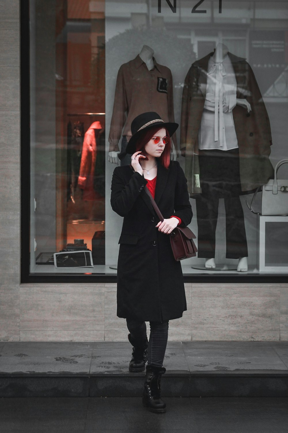 a woman standing in front of a store window talking on a cell phone