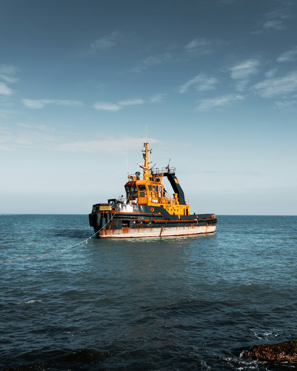 black-and-yellow tugboat on calm water during daytime