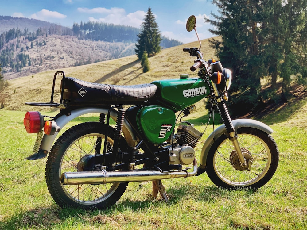 green standard motorcycle parked in green field