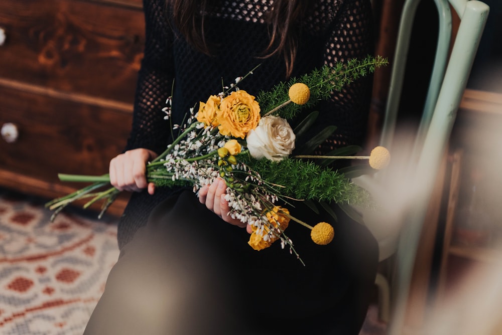 person carrying yellow and white rose bouquet