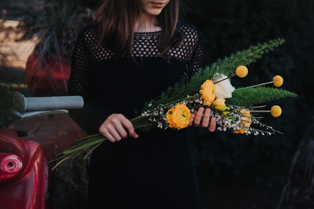 woman holding bouquet of white and yellow flowers