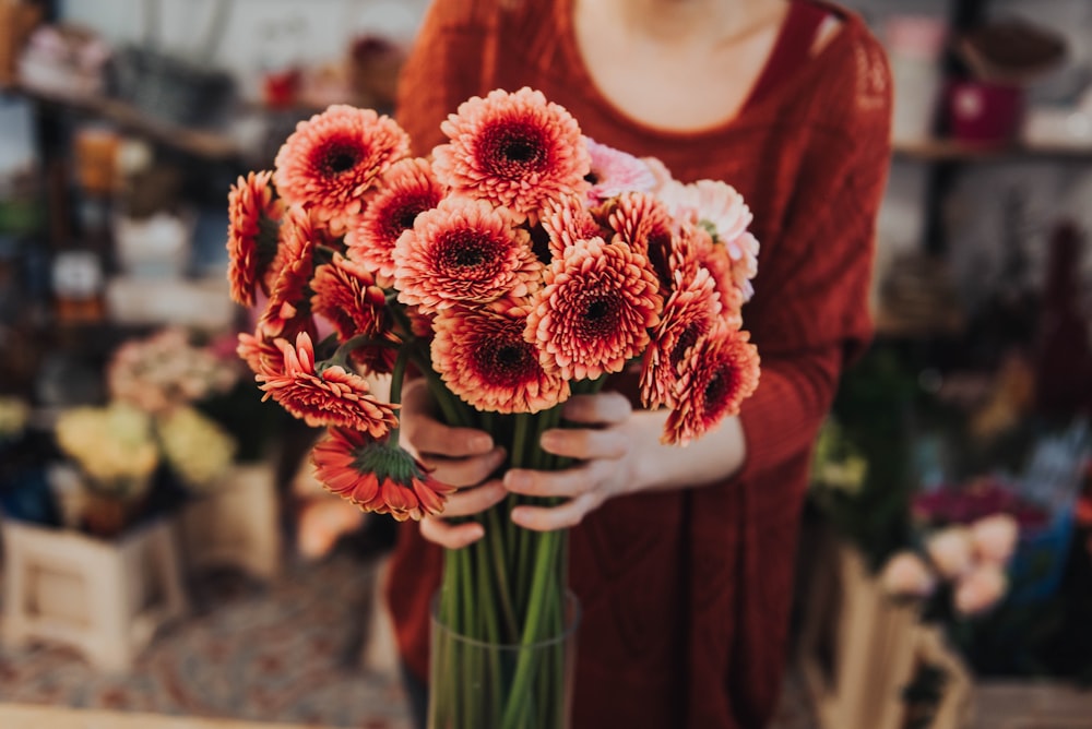 selective focus photo of woman holding pink-petaled flower bouquet