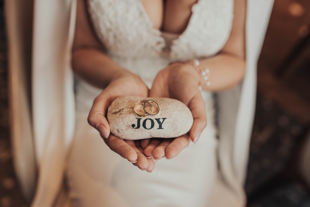 woman wearing white dress holding joy stone with couple rings