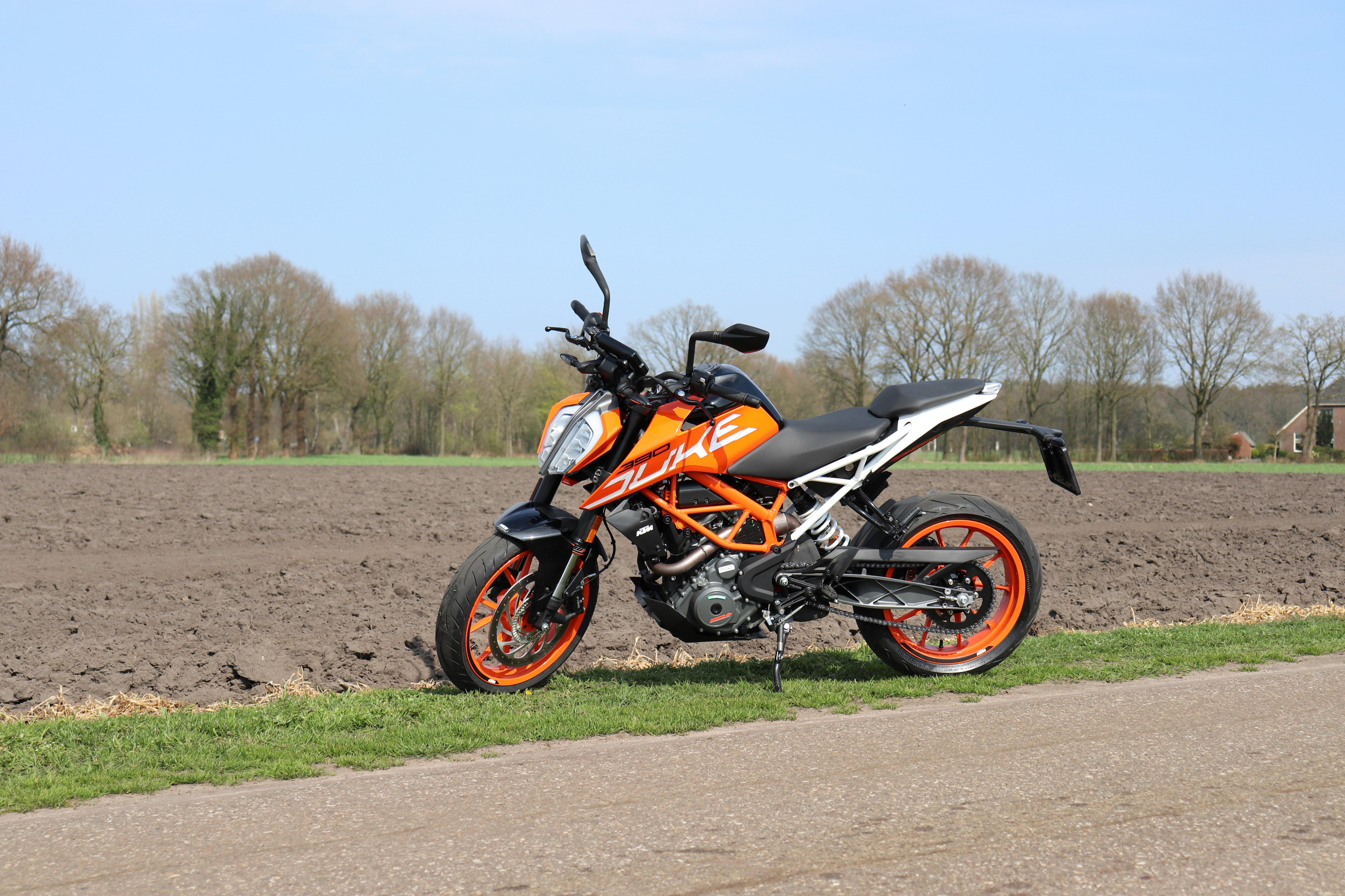 red and white naked motorcycle parked on farm road
