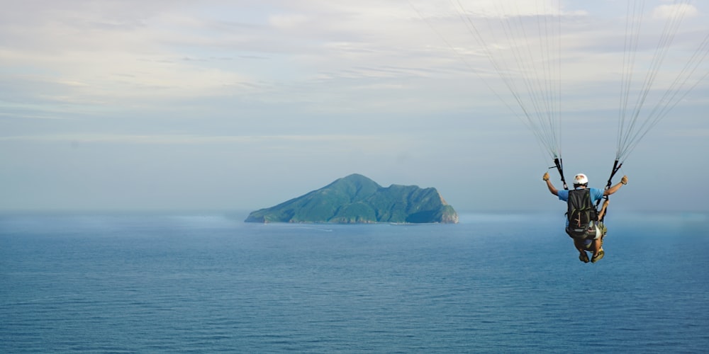 man maneuvering his parachute above sea