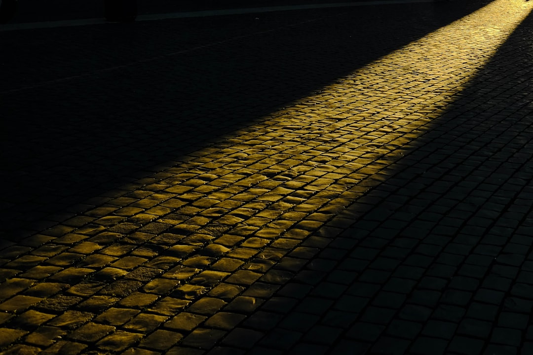 a person walking down a street at night, Observing light beaming on the path of cobblestone in Rome.
