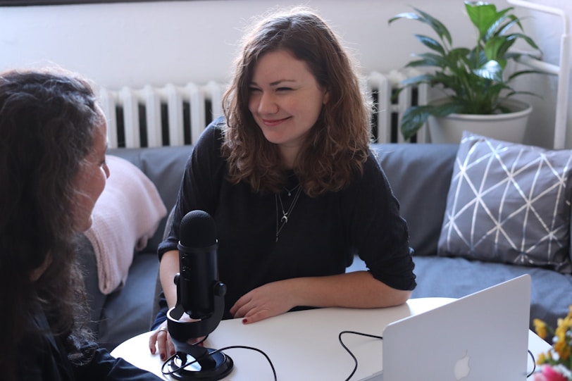 woman in black half-sleeved shirt sitting while facing woman. podcast. influencer. content 