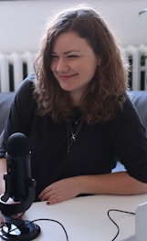 woman in black half-sleeved shirt sitting while facing woman and smiling