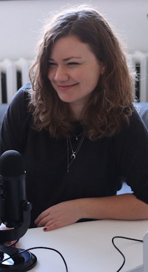 woman in black half-sleeved shirt sitting while facing woman and smiling