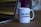 A white ceramic mug featuring the slogan 'THE FUTURE IS FEMALE' is placed on a wooden table. There is a visible lipstick mark on the rim of the mug. Beside the mug, part of an open laptop is visible, displaying what appears to be soundwave patterns on the screen.