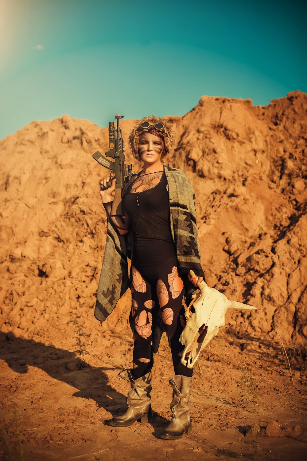 woman holding automatic rifle holding cattle skull at the rocky mountain