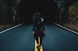 woman wearing black jacket walking on road